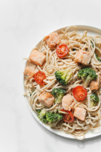 Meal-prep containers with salmon, broccoli, rice and colorful vegetables.