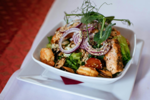 Grilled salmon with leafy greens and whole-grain sides on a rustic table