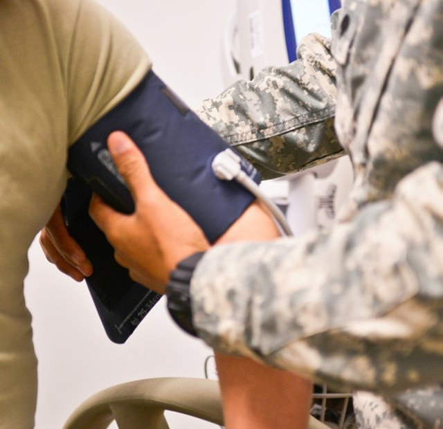 Nurse measuring a patient’s blood pressure with arm cuff and stethoscope