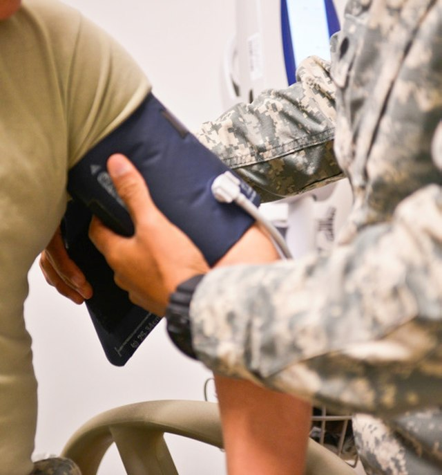 Nurse measuring a patient’s blood pressure with arm cuff and stethoscope