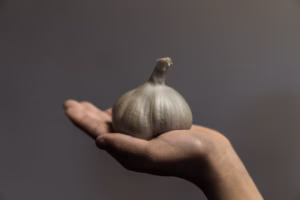“Hand holding peeled garlic cloves, close-up.”