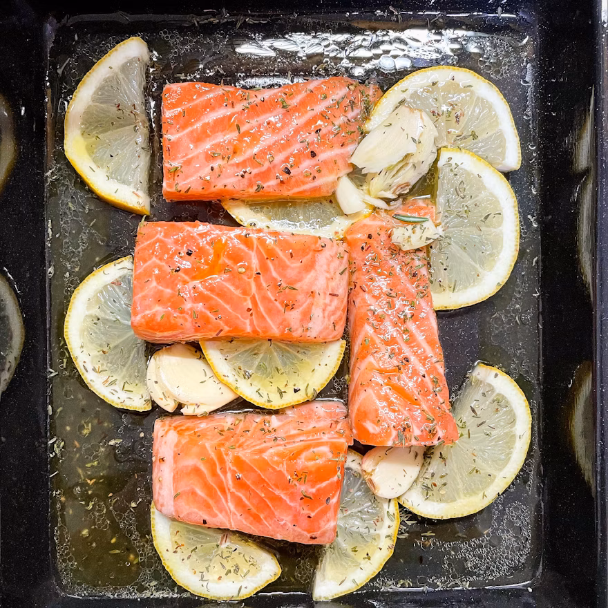 “Raw salmon fillet with lemon and herbs on a cutting board, representing omega-3 healthy fats”