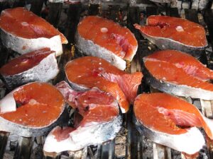 “Salmon fillets that are cut and placed on a grill.”