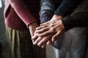 Closeup of several seniors’ hands stacked together in a gesture of support.