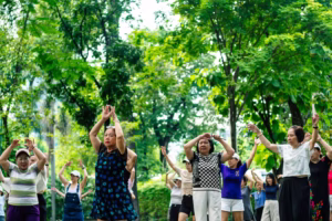 Group of older adults practicing gentle exercise together outdoors in a park.