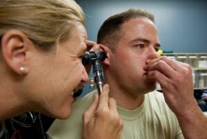 clinician observing a patient performing the Valsalva maneuver during ear exam
